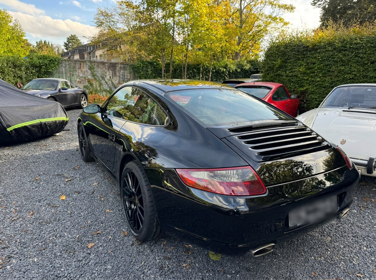 Rear three-quarter view of a black Porsche 997 Carrera on gravel